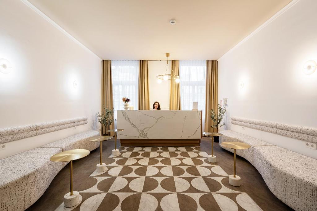 Reception lounge with marble desk, curved sofas and patterned rug at La Maison Parliament