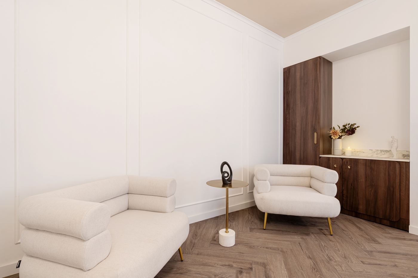Seating corner with cream armchairs and walnut cabinetry